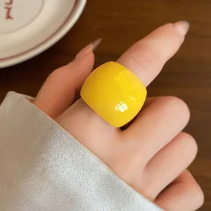 Primo piano di un anello in resina giallo vibrante minimalista indossato sull'indice