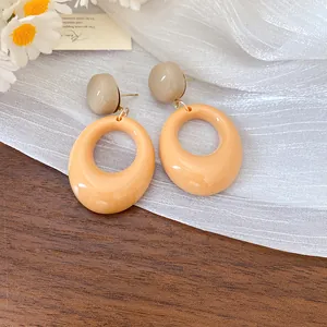 Detailed close-up of retro oval resin dangle earrings with peach and beige tones.
