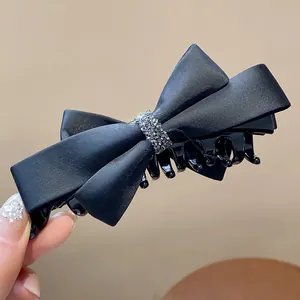 Gros plan détaillé d'une pince à cheveux nœud en satin noir ornée de strass brillants