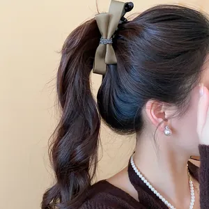 Vue détaillée latérale d'une élégante pince à cheveux nœud en satin brun sur une queue de cheval