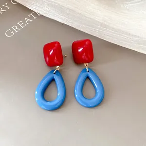 Close-up of retro resin drop earrings in vibrant red and blue geometric shapes