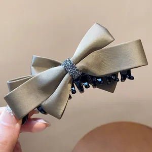 Détail d'une pince à cheveux en satin champagne avec une bande centrale en strass brillants