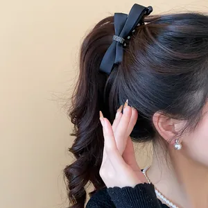 Gros plan d'une barrette à nœud en satin noir élégante sur une queue de cheval haute