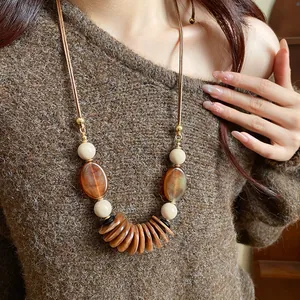 Vue détaillée d'un collier ethnique rétro avec pendentifs ambrés sur un pull marron.