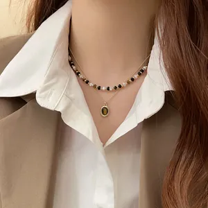 Primo piano della collana a due strati con perle occhio di tigre su colletto bianco.