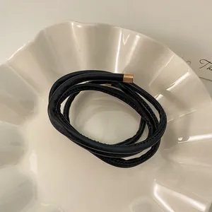 Elegant black leather wrap cord accessory with golden metal end tips