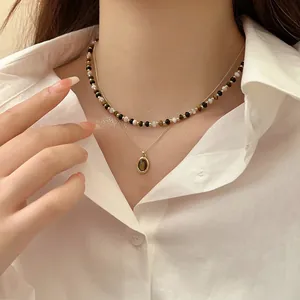 Primo piano di una collana a doppio strato placcata in oro con perle occhio di tigre e ciondolo