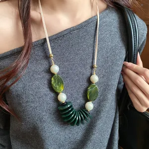 Gros plan d'un collier ethnique avec perles en résine verte et fausses perles sur cordon