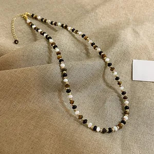 Dettaglio ravvicinato di collana di perline occhio di tigre e bianche dorate