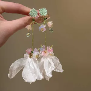 Detailed view of forest style earrings featuring white chiffon flowers and green beads