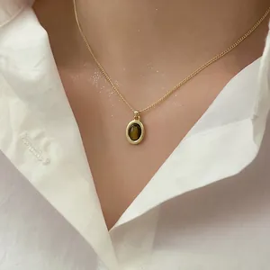 Primo piano di una collana vintage placcata oro con ciondolo ovale in occhio di tigre.