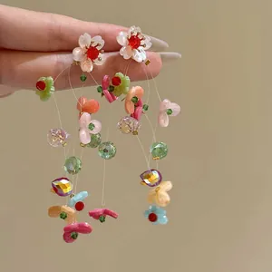 Close-up of elegant colorful acrylic floral tassel earrings with soft chiffon petals