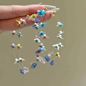 Macro view of forest style hoop earrings featuring colorful chiffon flowers and acrylic beads.