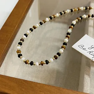 Dettaglio macro di una collana vintage con pietre occhio di tigre e perline placcate oro