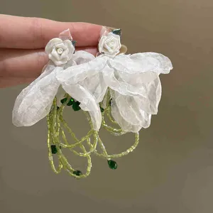 Detail of handmade chiffon flower earrings with light green bead tassels and rose accents