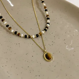 Primo piano che mostra i dettagli della collana placcata in oro con ciondolo occhio di tigre