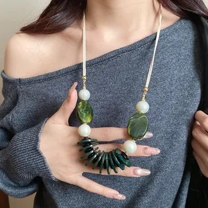 Gros plan d'un collier de style ethnique avec perles de marbre vert et nacre sur un mannequin.