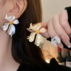 Primer plano de pendientes de flores vintage en blanco y oro usados por una modelo