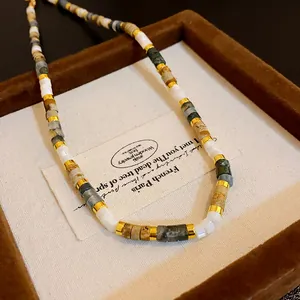 Detail shot of a retro beaded necklace with natural stone and gold metal accents.