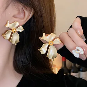 Vista detallada de pendientes de botón con flor vintage en oro mate usados por modelo