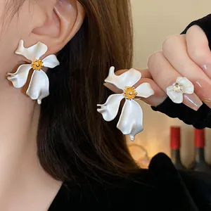 Primer plano de elegantes pendientes de flores blancas con pétalos ondulados