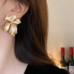 Primer plano de elegantes pendientes de botón vintage con forma de flor dorada mate