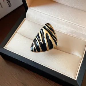 Vista detallada de un anillo triangular vintage dorado con rayas de esmalte negro