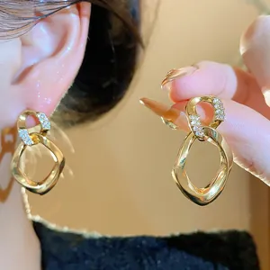 Primer plano de pendientes geométricos dorados con circonitas y diseño retorcido