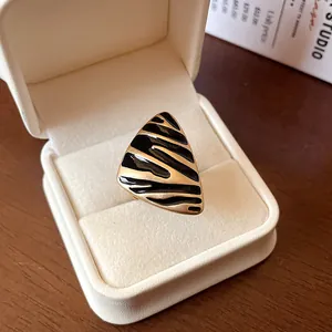 Primer plano de un anillo vintage triangular con rayas de esmalte negro en caja