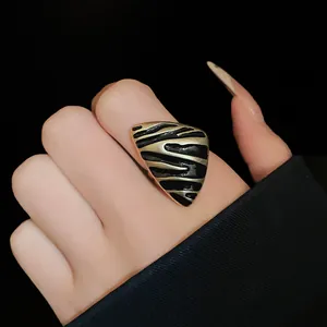 Detalle macro de un anillo abierto triangular vintage con rayas de esmalte negro
