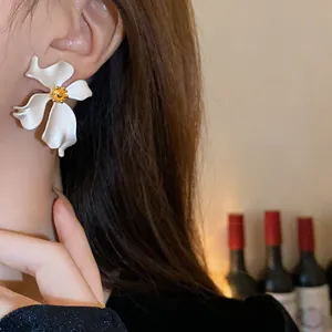 Detalle de elegantes pendientes de flores blancas vintage con centro dorado en oreja.