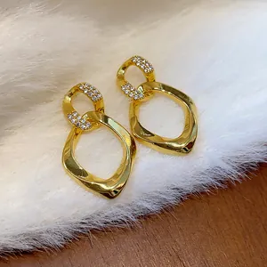 Vista detallada de los elegantes pendientes de circonita dorados con diseño de rombo