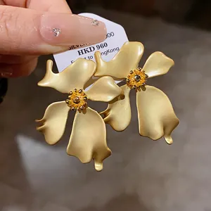 Primer plano de pendientes de flores vintage en oro mate con elegante textura de pétalo