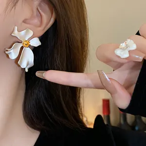 Primer plano de pendientes vintage de flores blancas con centro dorado en la oreja