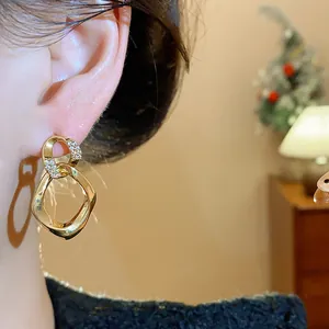 Detalle de pendientes dorados retorcidos con pavé de circonitas brillantes