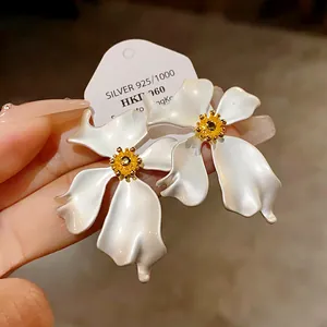 Vista detallada de elegantes pendientes de flores blancas mate con agujas de plata
