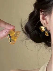 Primo piano di orecchini vintage a farfalla dorati con strass indossati sull'orecchio