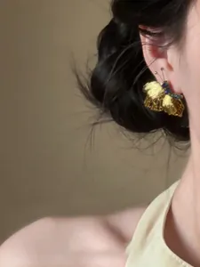 Vista dettagliata di un orecchino a farfalla dorato vintage con strass scintillanti.