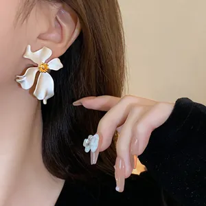 Vista detallada de elegantes pendientes de flor blanca vintage con un centro dorado