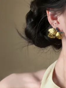 Dettaglio degli eleganti orecchini a farfalla vintage in oro con strass verdi scintillanti.