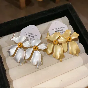 Vista detallada de elegantes pendientes vintage con forma de flor en blanco y oro