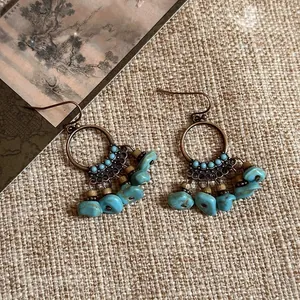 Vue détaillée de boucles d'oreilles ethniques vintage avec créoles et pierres turquoises