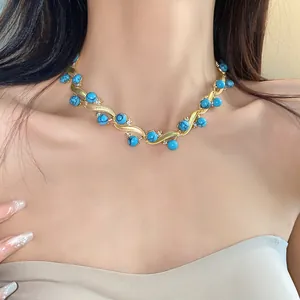 Detailed shot of a vintage turquoise and gold wavy necklace worn by an elegant model