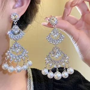 Close-up of elegant fan-shaped earrings with sparkling crystals and pearl tassels.