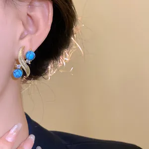 Close-up of vintage turquoise bead earrings with gold leaf and rhinestone accents