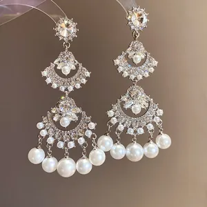 Close-up detail of vintage fan-shaped chandelier earrings with rhinestones and pearls