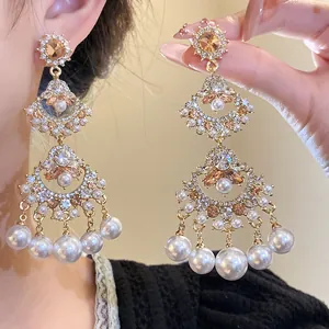 Close-up of vintage fan-shaped chandelier earrings with sparkling rhinestones and pearls.