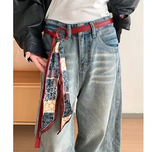 Elegante cintura in pelle rossa con foulard di seta floreale vintage su jeans blu