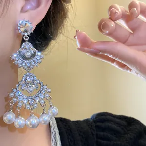 Close-up detail of vintage silver fan earrings featuring sparkling rhinestones and white pearls