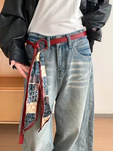 Dettaglio di una cintura in pelle rossa con un accessorio in sciarpa di seta a fantasia